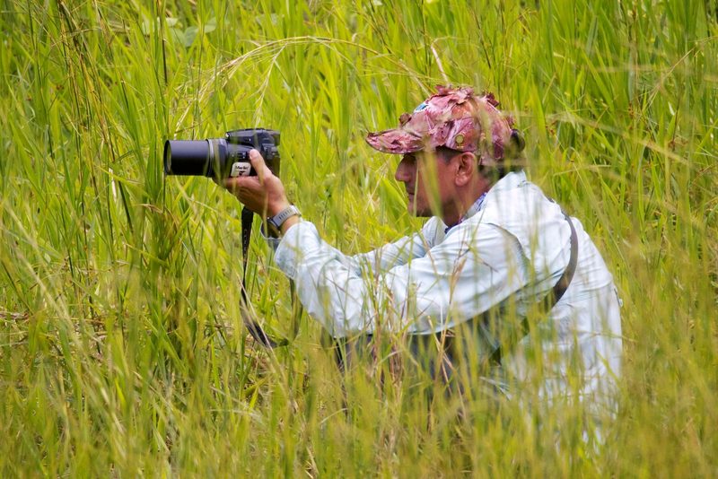 Egor Merik Sánchez photographing with a camera in tall grass