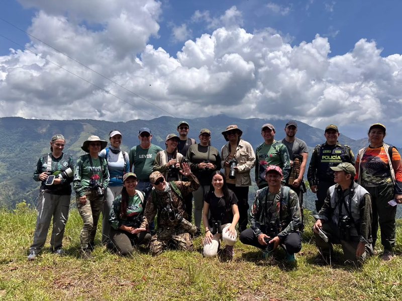 Egor Merik Sánchez, kneeling in front in a red cap and camouflage shirt, with the VillAves field-trip group on a hilltop